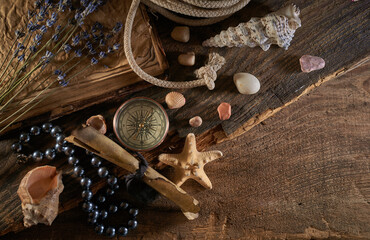 A marine concept with a bottle, starfish, seashells, rope, compass and paper scroll, pirate still life