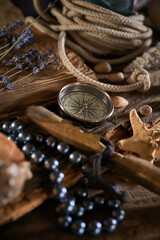A marine concept with a bottle, starfish, seashells, rope, compass and paper scroll, pirate still life