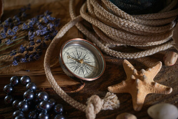 Fototapeta na wymiar A marine concept with a bottle, starfish, seashells, rope, compass and paper scroll, pirate still life
