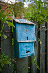 An old rusty mailbox is hanging on the fence.