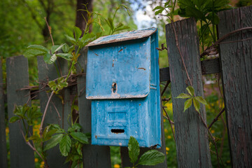 An old rusty mailbox is hanging on the fence.