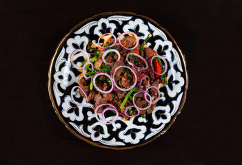 Plate with chopped meat and vegetables on a black background. Asian cuisine