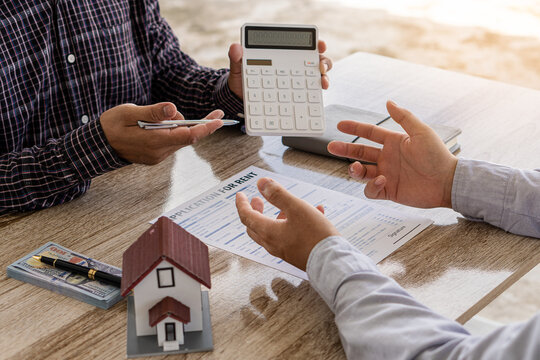 Sales representatives and new homeowners sign a home purchase or rental contract on the table. Real estate concepts or bank officers explain loan interest to customers with home or office loan contrac