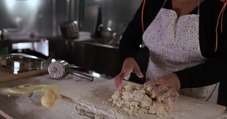 Woman using potato press for fresh made gnocchi inside pasta factory