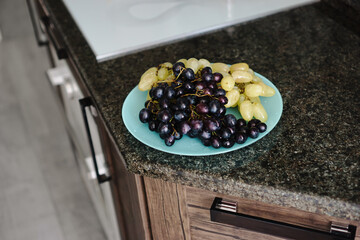 Two bunches of grapes on plate in kitchen. Red and green grape. Clean eating concept, healthy snacks.