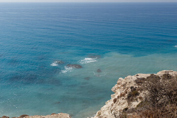 Sea waves on the wild rocky coast. Beautiful seascape. Travel concept. Seascape on the background of the wild rocky coast. Wild beach, azure water and rocks. Mediterranean sea, Cyprus. Postcard view