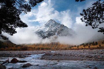 Mount Tihtengen covered by thick clouds and framed by conifers