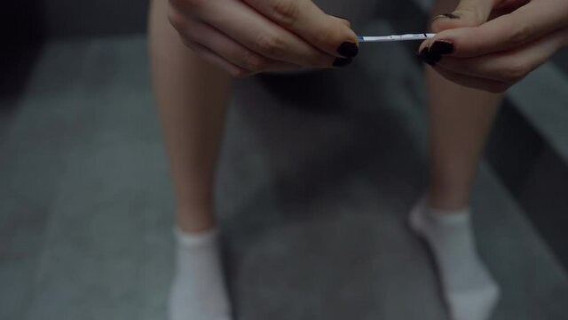 Female teenager looks at the results of a positive pregnancy test
