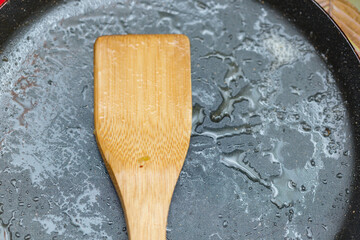 Dirty frying pan with butter and wooden spoon