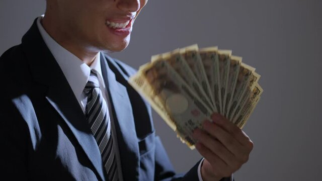 お札の団扇を扇ぐ中年ビジネスマン（ビジネス・金融）