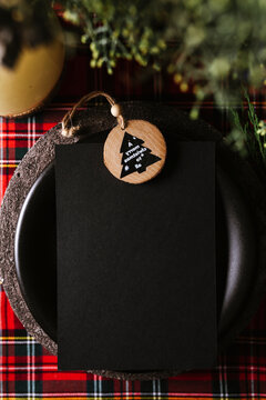 Christmas table setting with empty menu on checkered red tablecloth