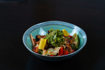Salad with meat and vegetables on a black background