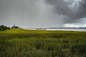 Fototapeta na wymiar Rapidly moving rain storm over Charleston Harbor, with USS Yorktown at left and storm clouds overhead.