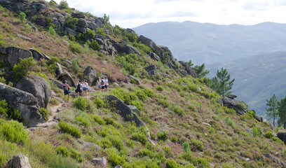 Fototapeta na wymiar Grupo de pessoas a fazer uma caminhada pela encosta de uma montanha - trilho montanhoso - dia quente de verão