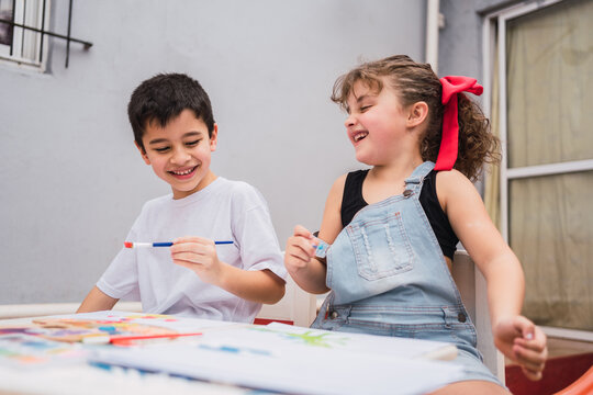 Cheerful children painting at table