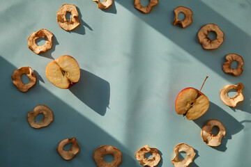 Dried sliced apple chips and fresh apples - healthy alternative snacks on the trendy shadows. Proper nutrition concept. Top view. Copy space.