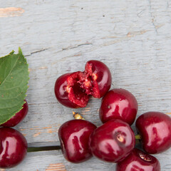 Red cherry green leaves on light blue wood table, copy space