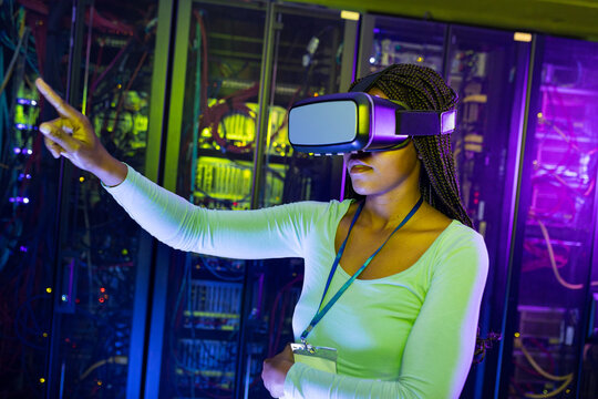 African american female computer technician wearing vr headset and working in server room