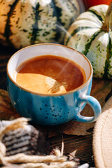 autumn still life with a cup of coffee. autumn leaves, pumpkins, a plaid and a hat on a wooden table and a cup of hot aromatic coffee in the center.