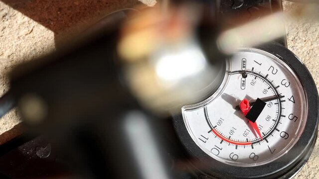 Close-up view of a pump with manometer blowing air into a valve of wheel.