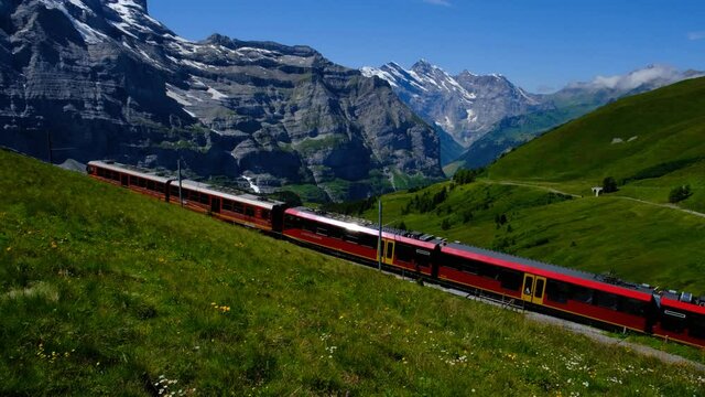 red alpine railway from Kleine Scheidegg to Jungfraujoch. Swiss mountains with Jungfrau, Moench and Eiger. Great scenic view.