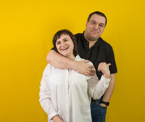 happy married couple hugging on yellow background