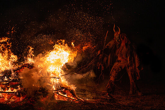 Burning logs with Krampus figure at night