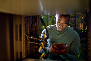 African american male computer technician using tablet and working in server room