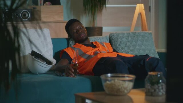 Sleepy black worker watching TV