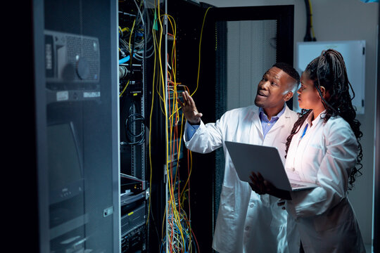 African american computer technicians using laptop working in server room