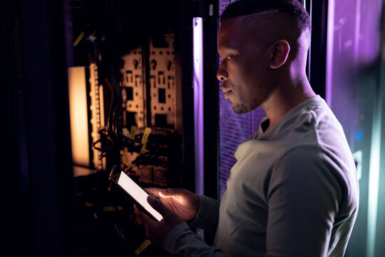 African american male computer technician using tablet and working in server room