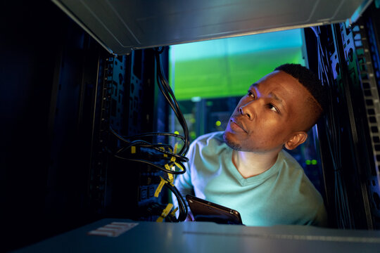 African american male computer technician using tablet and working in server room - Powered by Adobe