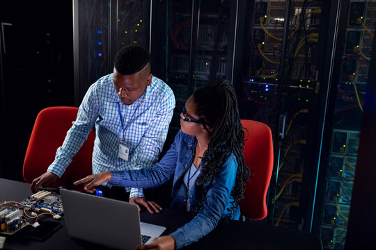 African american computer technicians using laptop working in server room