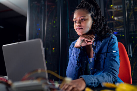 African american female computer technician using laptop working in server room