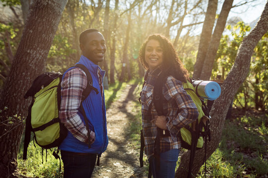 Happy diverse couple with backpacks hiking in countryside