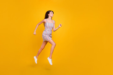 Fototapeta na wymiar Full length body size woman smiling jumping high happy running fast isolated vivid yellow color background