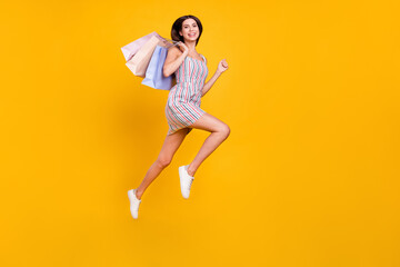 Fototapeta na wymiar Full length body size woman smiling jumping running on sale with bags laughing isolated vivid yellow color background
