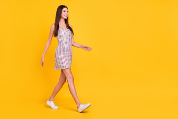 Fototapeta na wymiar Full length body size woman smiling happy walking in striped dress looking copyspace isolated vivid yellow color background