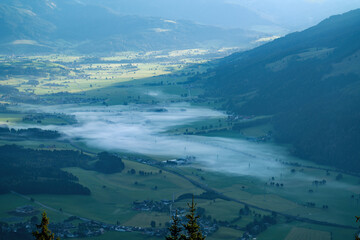 view of a misty valley with sunlight in the background