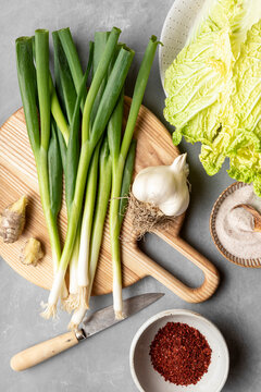 Ingredients to make kimchi, including napa cabbage, green onions, and gochugaru, shot in bright lighting