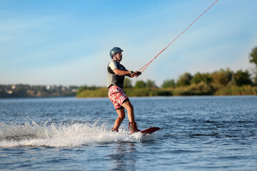 Teenage boy wakeboarding on river. Extreme water sport