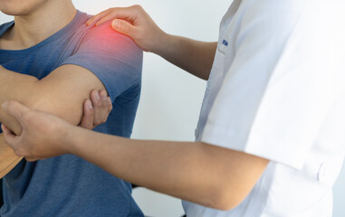 Obraz premium A man with shoulder pain goes to the doctor for treatment. The doctor is diagnosing the patient's shoulder pain.