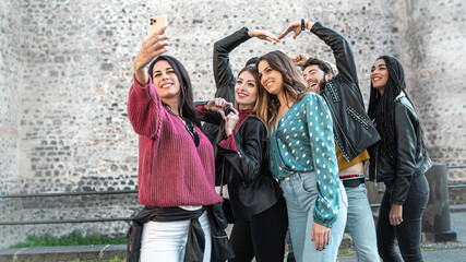 Group of young friends in the ancient city center taking a selfie with the smart phone - seven...