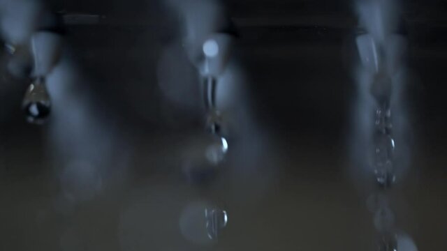 Drops of water dripping from rows ow small plastic nozzles