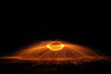Spinning and burning Steel wool sparkle fire in the circle shape with long speed shutter shoot glowing light line to the ground.