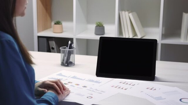 Internet conference. Video meeting. Work from home. Business analyzing. Woman accounter discussing data at digital tablet with copy space blank mockup screen at office workspace.