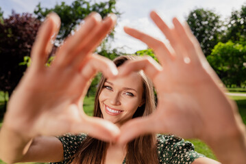 Photo of romantic dreamy girlfriend make heart gesture cover face wear green dress nature park...