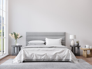 Empty white wall for print or poster mockup in modern neutral gray bedroom interior with wood floor, rug with geometric pattern, bedside tables, lamps, decor and plants.
