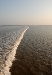 Obraz premium The tidal bore on the estuary of the Qiantang River. Northern bank of the Qiantang River near Hangzhou in Zhejiang Province, China. The southern bank is visible in the distance.