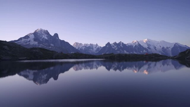 Dawn at Lac des Cheserys, with the first sunlight shining on the Mont Blanc. Panning shot.